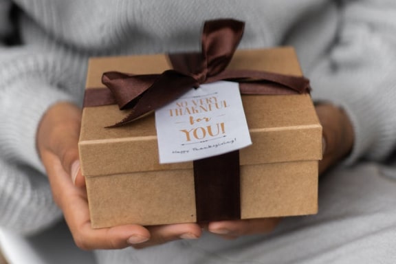 hands holding brown box with ribbon