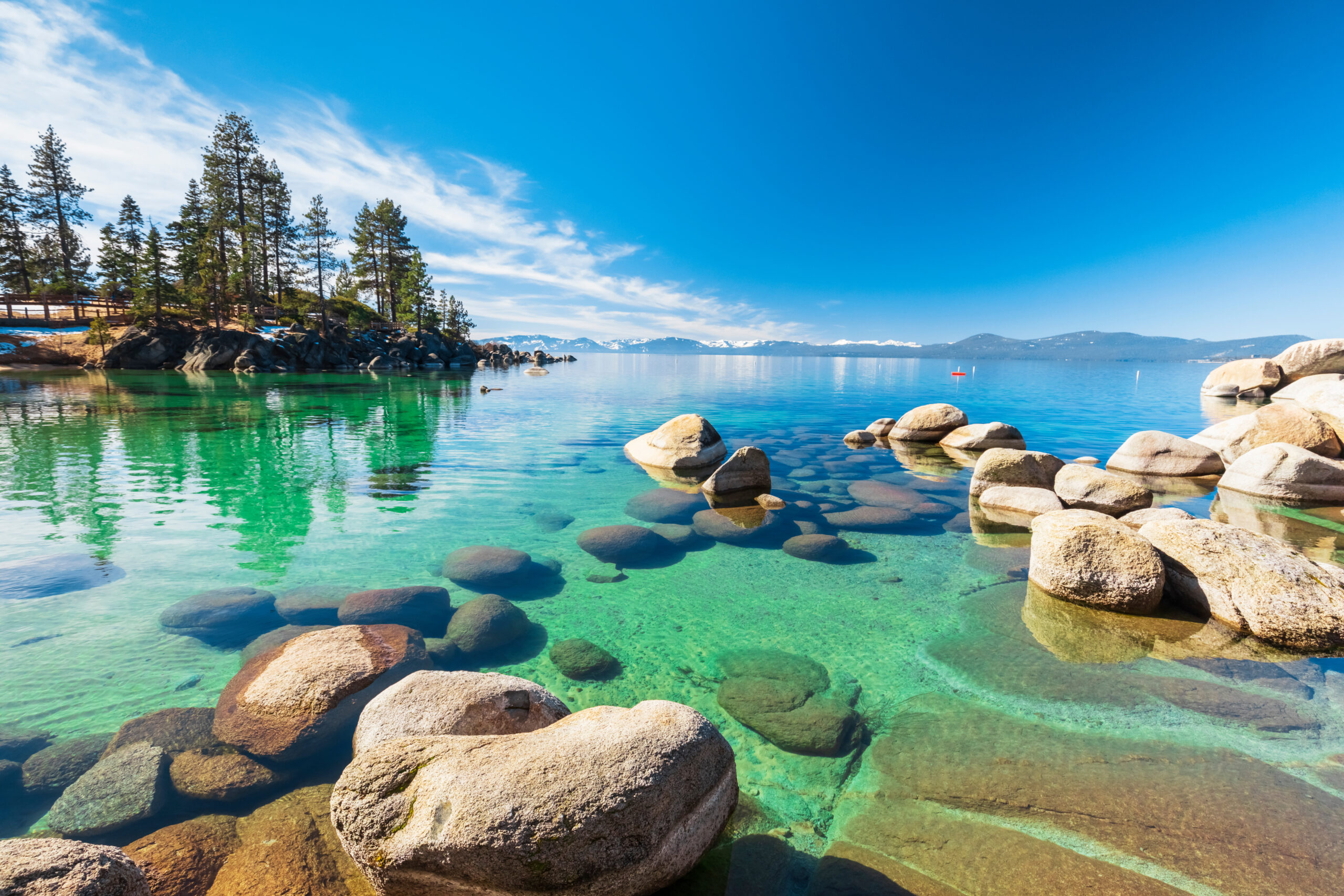 Lake Tahoe rocky shoreline in sunny day, beach with blue sky ove Red