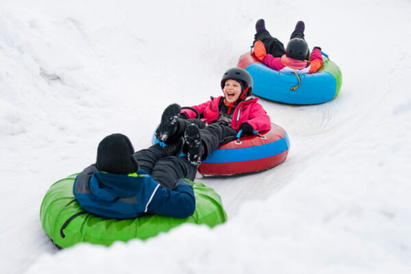 Kids on snow tubes downhill at winter day